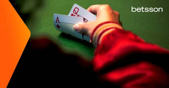 Cabecera que explica qué es el bacará, con una mano levantando dos naipes sobre el tapete.