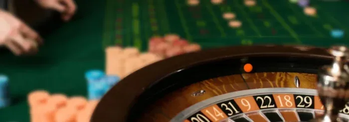 Fotografía de una rueda de ruleta en primer plano con el paño de apuestas desenfocado detrás.